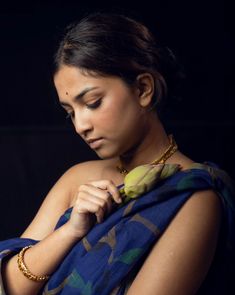 a woman in a blue sari is looking down at her cell phone while wearing a gold necklace