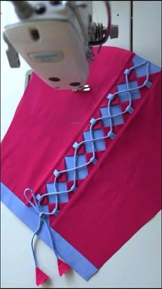 the sewing machine is next to a pink and blue piece of cloth that has been stitched together