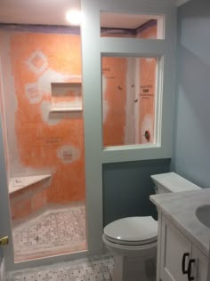 a bathroom that is being remodeled with orange paint on the walls and floor, along with a white toilet