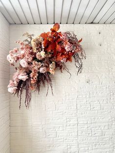 a bunch of flowers hanging from the ceiling in a room with white brick wall and metal slats