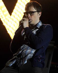 a man with glasses is singing into a microphone