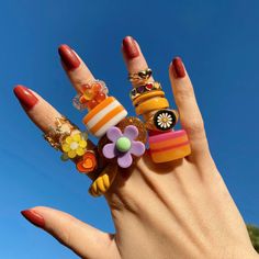 a woman's hand with four rings on it that have different designs and colors