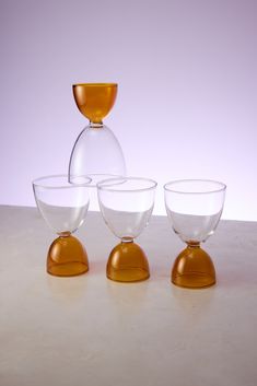 three glasses sitting on top of each other in front of a white wall and purple background