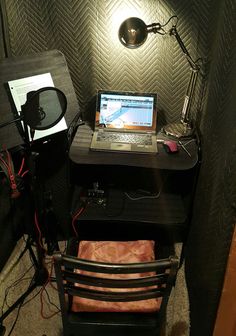 a laptop computer sitting on top of a wooden desk next to a speaker and light