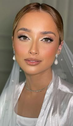 a woman wearing a white veil and earrings is posing for a photo in her wedding dress