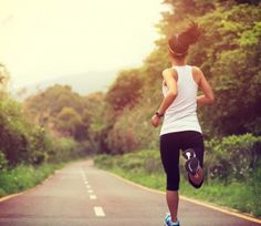 a woman running down the road with trees in the background