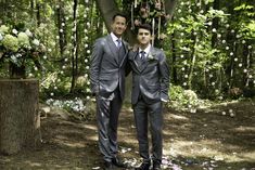 two men standing next to each other in front of a tree with flowers on it