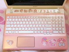 an open laptop computer sitting on top of a pink bed covered in hello kitty decals