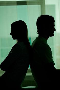 a man and woman sitting next to each other in front of a window