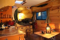 the inside of a small cabin with wood walls and flooring is lit by a candle