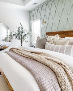 a bedroom with a bed, mirror and plant on the wall in front of it