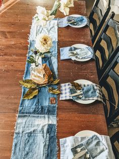 the table is set with denim napkins and flowers on it, along with plates and utensils