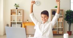 a woman sitting at a desk with her arms in the air