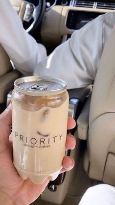 a person holding a drink in their hand while sitting in the back seat of a car