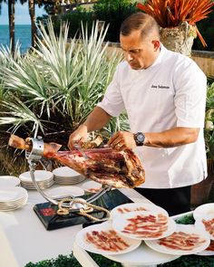 a man preparing food on top of a table with plates and utensils in front of him