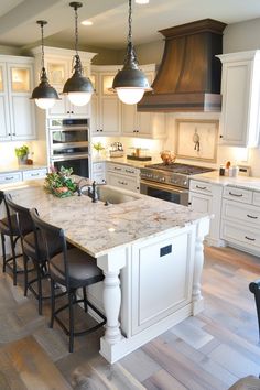 a large kitchen with an island in the middle and several lights hanging from the ceiling