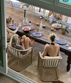 two women sitting at a table with plates of food on it and one woman taking a selfie