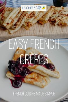 french crepes with blueberry sauce are on a white plate next to some bread