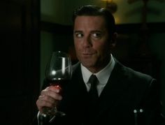 a man in a suit holding a glass of wine