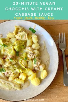 a white plate topped with pasta and artichokes on top of a wooden table