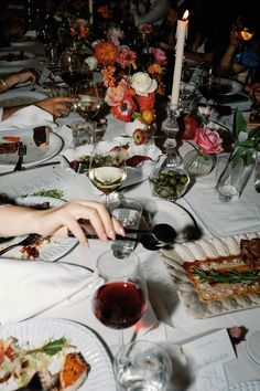 a group of people sitting at a table with food and wine glasses on top of it