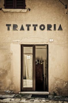 black and white photograph of the entrance to a store called tratteria in italy