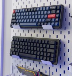 there are two black keyboards attached to the pegs that hold them in place on the wall