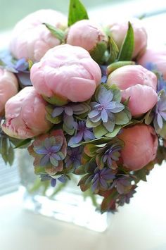 a bouquet of pink flowers sitting on top of a glass vase next to a window