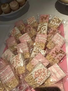 some pink and white treats in plastic bags on a table