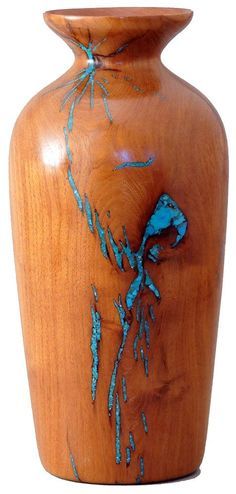 a wooden vase with blue paint on it's body and flowers painted on the side