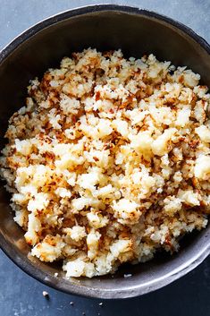 a bowl filled with rice and seasoning on top of a blue tablecloth next to a spoon