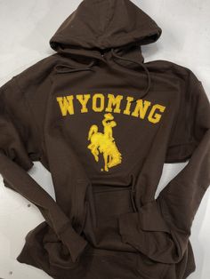 An original design by Pink Geeks Boutique. Gold hoodie embroidery and Appliqué  Unisex size  Sizes available s-xl University Of Wyoming, Hoodie Embroidery, Brown Hoodie, Embroidery Hoodie, Gold Embroidery, Wyoming, Hoodie Sweatshirt, Original Design, Clothing Items