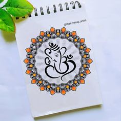 a spiral notebook with an image of the hindu god ganesh on it next to some leaves