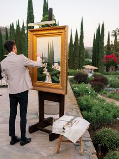 a man standing next to an easel with a painting on it