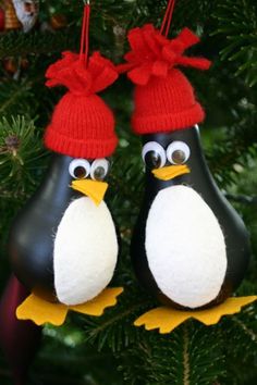 two penguin ornaments hanging from a christmas tree