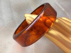 This flat translucent bangle bracelet is made of Bakelite/Catalin (phenolic resin) and features a lovely marbled swirl pattern of dark brown in a orangey brown "root beer" color. It has been simichrome tested and positively identified as genuine Bakelite/Catalin. It measures 3" x 15/16" and has small signs of wear and age all over, but is generally in good condition. Deco Hippie, Midcentury Boho, Boho Art Deco, 1950s Bracelet, Bakelite Jewelry, Vintage Bakelite, Swirl Pattern, Boho Art, Small Signs