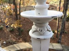 a white bird bath sitting on top of a wooden post