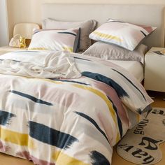 a bed with white and yellow comforters on top of it next to a rug