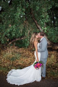 a bride and groom kissing under a tree