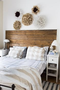 a bed with white sheets and pillows on top of it next to a wooden headboard