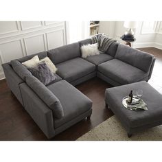 a grey sectional couch with pillows and a bottle of wine on the end table in front of it