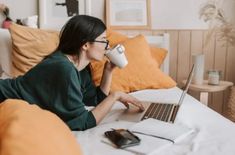 a woman drinking coffee while using her laptop