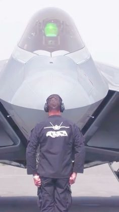 a man standing in front of a jet with its door open and headphones on