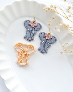 two elephant cookie cutters sitting on top of a white plate next to dried flowers