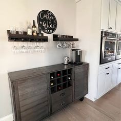 a kitchen with wine glasses on the cabinets and a coffee maker in the corner next to it