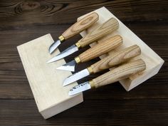 five knives are sitting on a wooden block