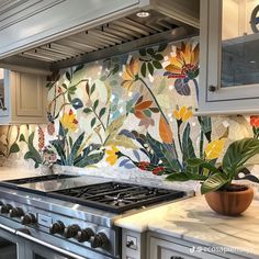 a stove top oven sitting inside of a kitchen next to a wall covered in flowers