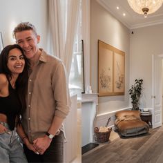 a man and woman standing next to each other in front of a living room filled with furniture