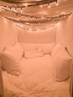 a bed with white sheets and pillows in a room that has lights on the ceiling