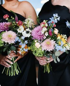 two women in black dresses holding bouquets of flowers